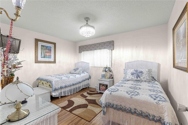 bedroom featuring a textured ceiling, a notable chandelier, and hardwood / wood-style flooring