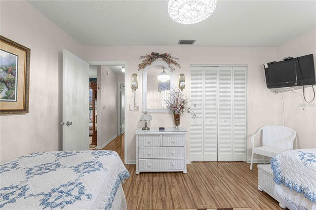 bedroom featuring light wood-type flooring, a closet, and a textured ceiling