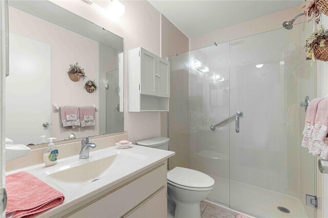 bathroom featuring tile patterned flooring, vanity, toilet, and walk in shower