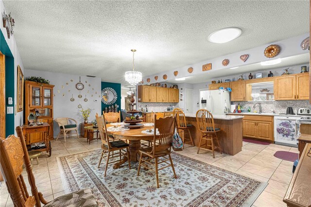 dining space with sink, an inviting chandelier, and a textured ceiling