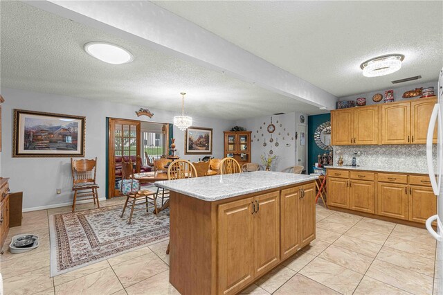 kitchen featuring hanging light fixtures, a kitchen island, tasteful backsplash, and a textured ceiling