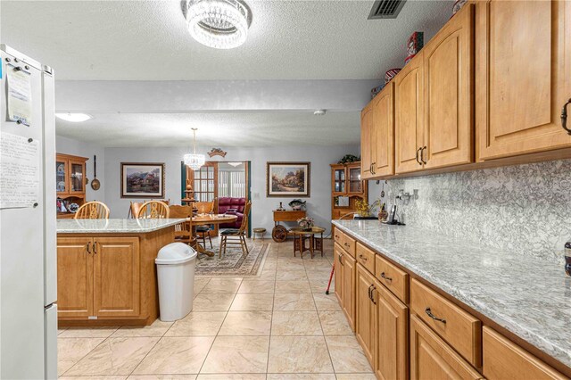 kitchen featuring decorative backsplash, a textured ceiling, a notable chandelier, and hanging light fixtures