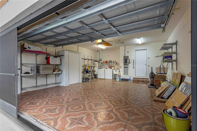 garage featuring a garage door opener, water heater, electric panel, and washer and dryer