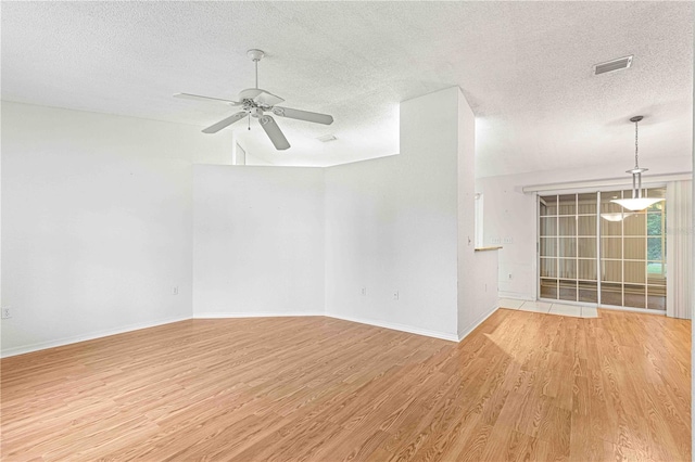 spare room with lofted ceiling, ceiling fan, a textured ceiling, and light hardwood / wood-style flooring