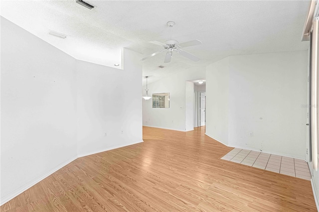 spare room with a textured ceiling, light hardwood / wood-style flooring, and ceiling fan