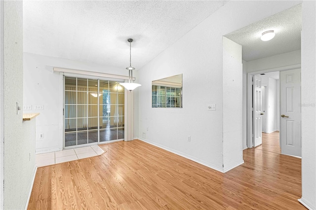 unfurnished room featuring a textured ceiling, wood-type flooring, and lofted ceiling