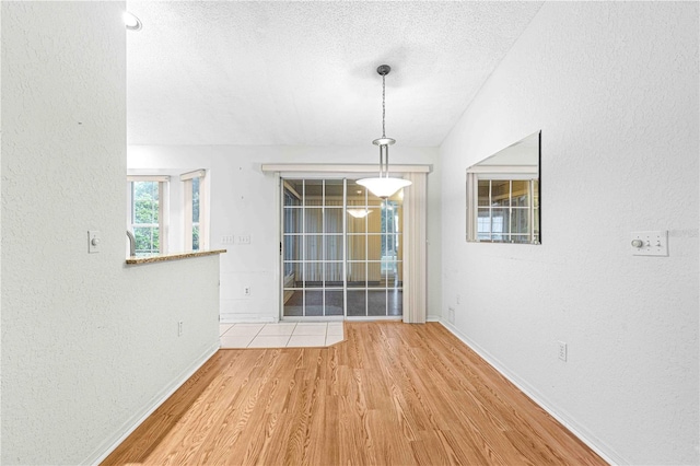 empty room with a textured ceiling and light wood-type flooring