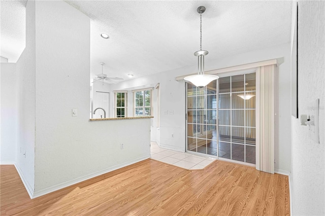 unfurnished room with light wood-type flooring, ceiling fan, sink, and a textured ceiling