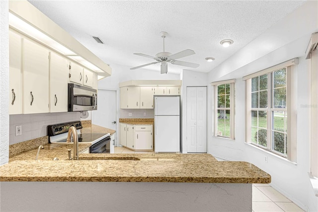 kitchen featuring vaulted ceiling, stainless steel appliances, kitchen peninsula, ceiling fan, and a textured ceiling