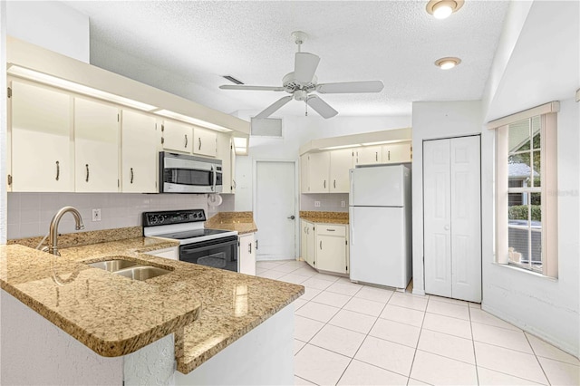 kitchen featuring white appliances, kitchen peninsula, light stone counters, ceiling fan, and vaulted ceiling