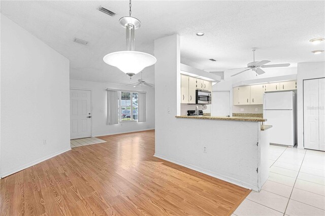 kitchen with white refrigerator, ceiling fan, light hardwood / wood-style floors, and kitchen peninsula