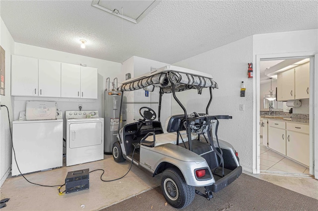 clothes washing area featuring washer and clothes dryer, electric water heater, sink, cabinets, and a textured ceiling