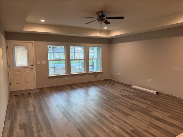 interior space featuring dark wood-type flooring, ceiling fan, and a tray ceiling