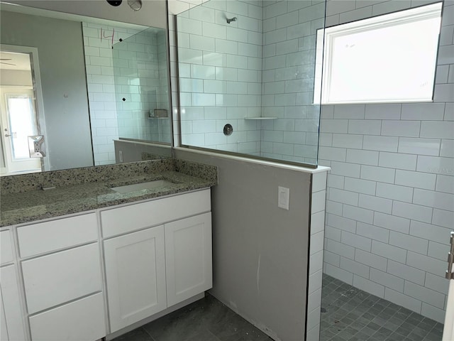 bathroom with a wealth of natural light, tiled shower, and vanity