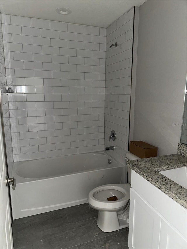 full bathroom featuring tile patterned floors, vanity, tiled shower / bath combo, and toilet