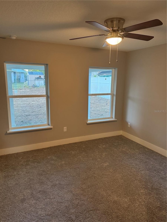 carpeted spare room featuring a wealth of natural light and ceiling fan