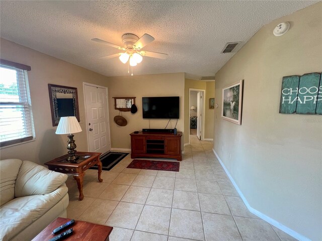 living room with ceiling fan, light tile patterned floors, and a textured ceiling