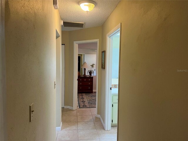 hall featuring a textured ceiling and light tile patterned flooring