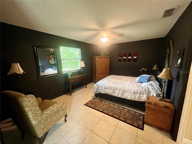 tiled bedroom with ceiling fan and a textured ceiling