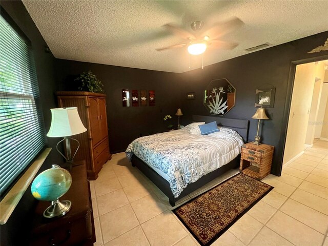 bedroom featuring ceiling fan, a textured ceiling, and light tile patterned floors