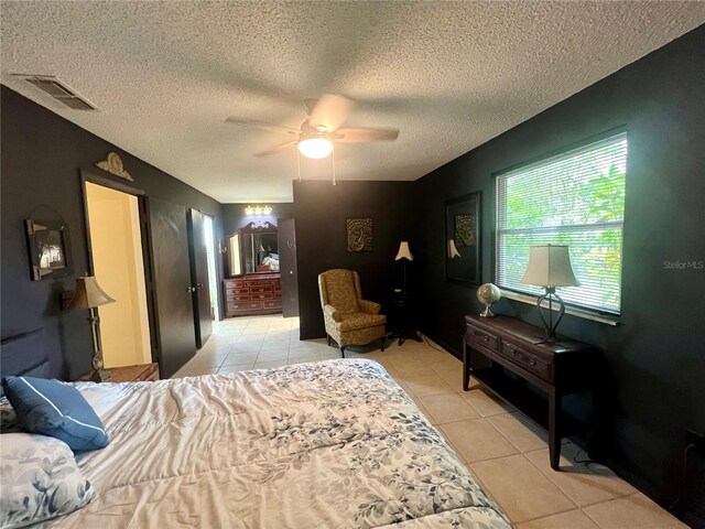 bedroom with ceiling fan, light tile patterned flooring, and a textured ceiling