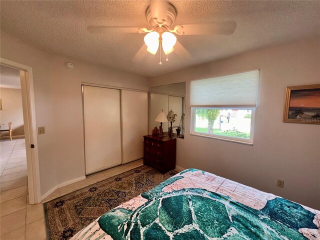 tiled bedroom featuring a textured ceiling, ceiling fan, and a closet