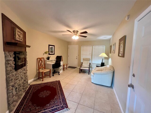 interior space with a stone fireplace and ceiling fan