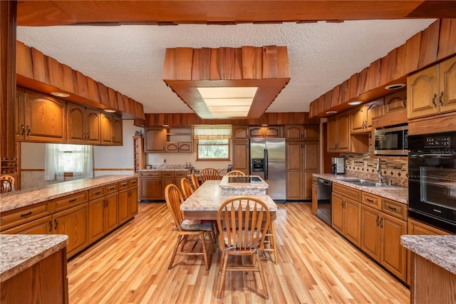 kitchen featuring a textured ceiling, light wood-type flooring, sink, and black appliances