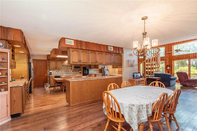 dining space with a notable chandelier, dark wood-type flooring, and a textured ceiling