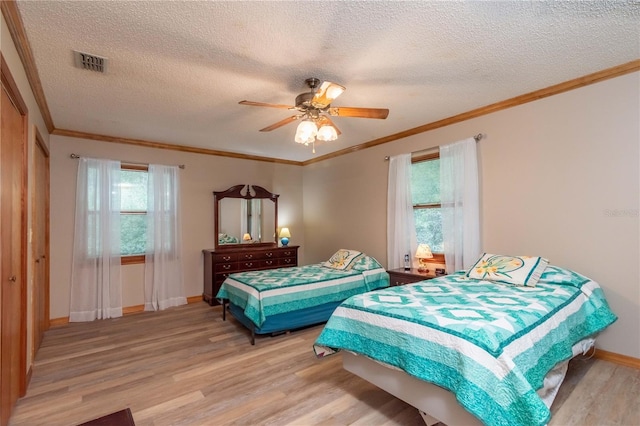 bedroom with light hardwood / wood-style flooring, multiple windows, ceiling fan, and a textured ceiling