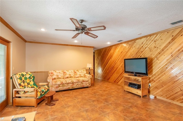 living room featuring a textured ceiling, crown molding, wooden walls, and ceiling fan