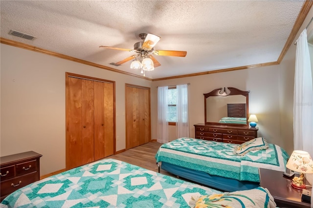 bedroom featuring light wood-type flooring, a textured ceiling, ornamental molding, and ceiling fan