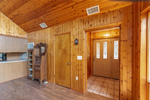 entryway featuring wooden walls, wood ceiling, vaulted ceiling, and light hardwood / wood-style flooring