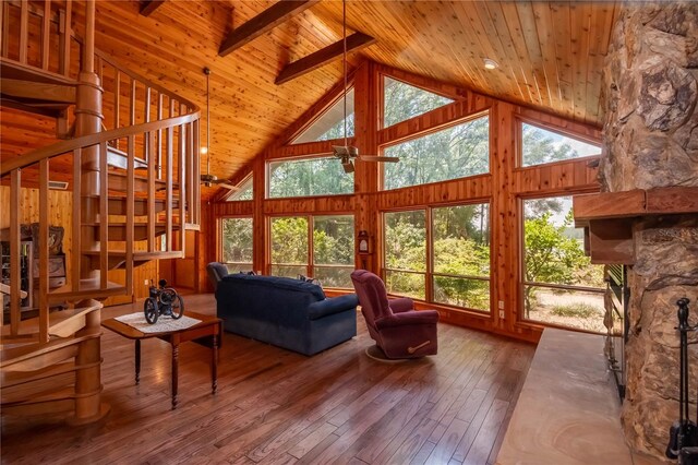 living room with a stone fireplace, plenty of natural light, hardwood / wood-style floors, and high vaulted ceiling