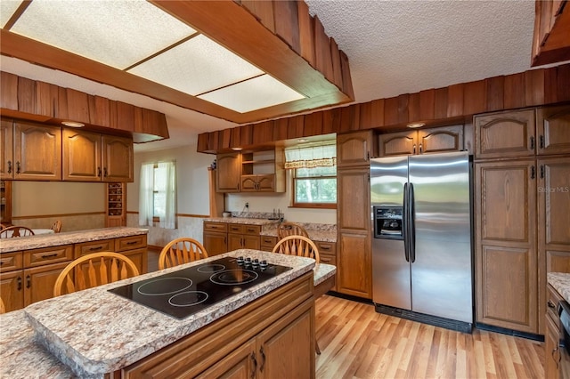 kitchen with black electric cooktop, a healthy amount of sunlight, stainless steel fridge with ice dispenser, and light hardwood / wood-style flooring