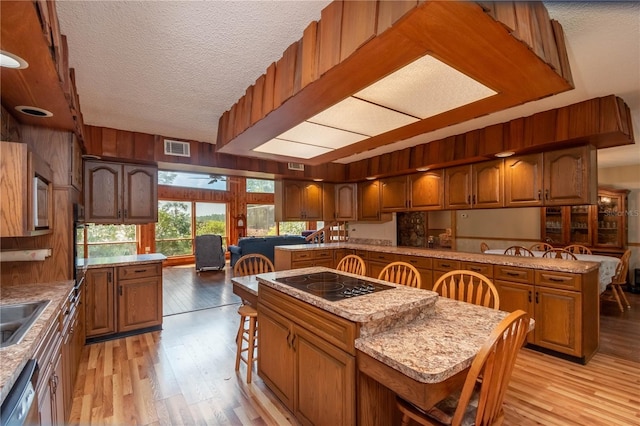 kitchen featuring a kitchen breakfast bar, light hardwood / wood-style floors, a kitchen island, a textured ceiling, and black appliances