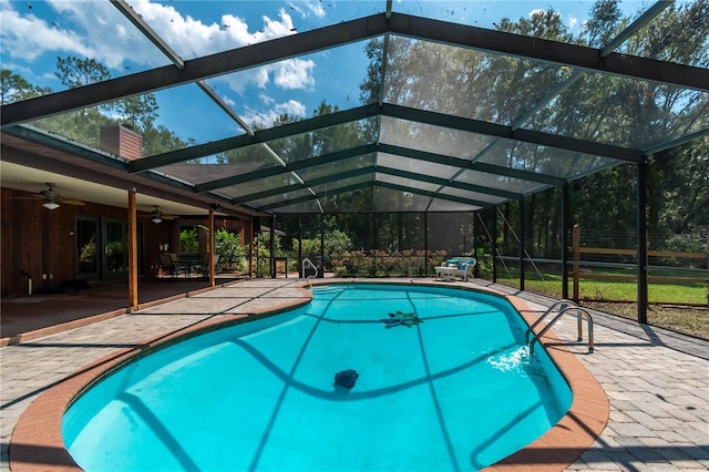 view of swimming pool featuring glass enclosure, ceiling fan, and a patio