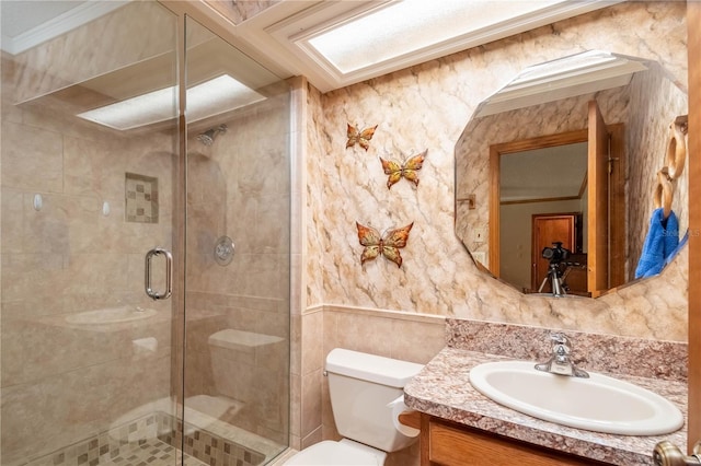 bathroom with tile walls, vanity, walk in shower, ornamental molding, and toilet