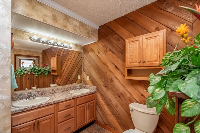 bathroom featuring vanity, a textured ceiling, ornamental molding, wooden walls, and toilet