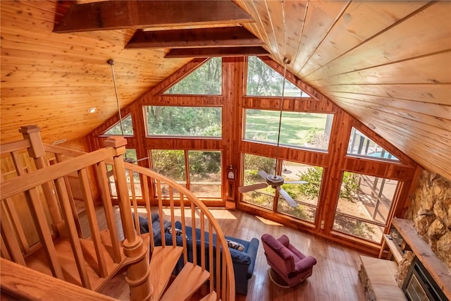 unfurnished living room with wooden walls, lofted ceiling with beams, hardwood / wood-style floors, and wooden ceiling