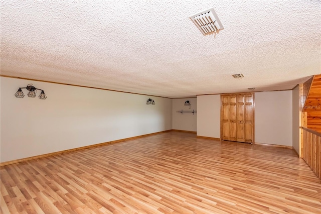 unfurnished living room with a textured ceiling and light wood-type flooring