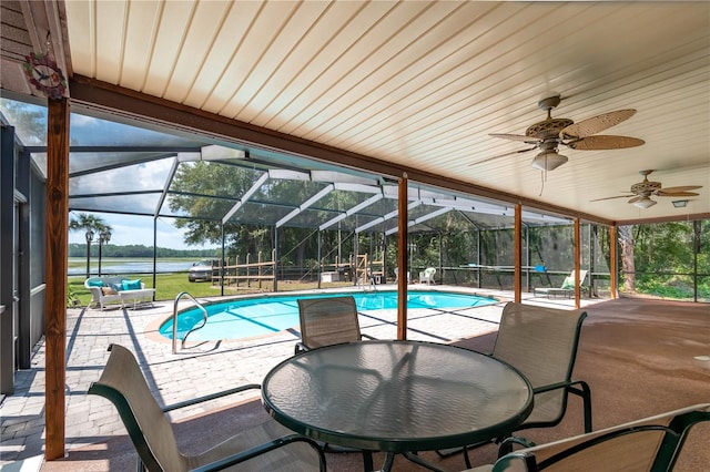 view of swimming pool featuring ceiling fan, glass enclosure, and a patio