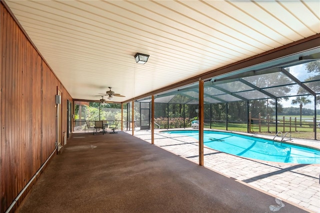 view of swimming pool featuring a patio, glass enclosure, and ceiling fan