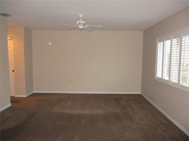 spare room with dark colored carpet and ceiling fan