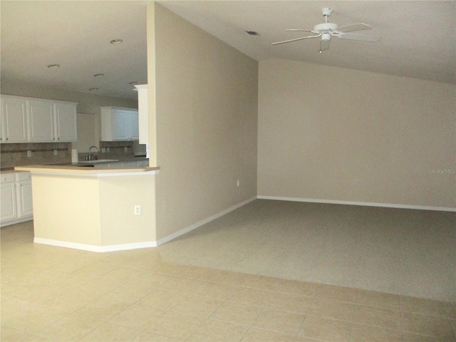 kitchen with ceiling fan, decorative backsplash, kitchen peninsula, and white cabinets