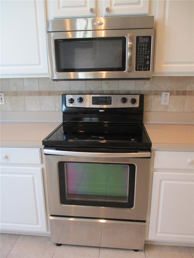 kitchen with backsplash, stainless steel appliances, light tile patterned floors, and white cabinets