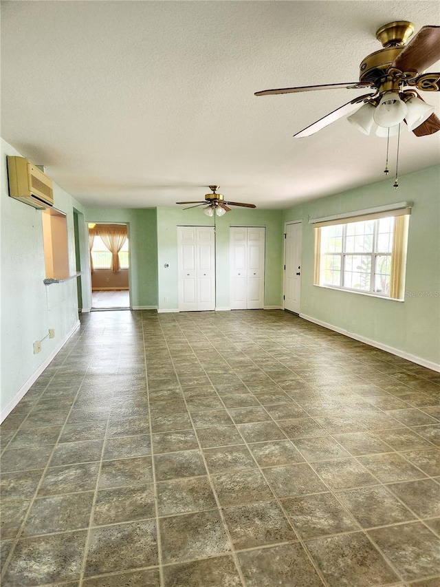 unfurnished living room with a wall unit AC and a textured ceiling