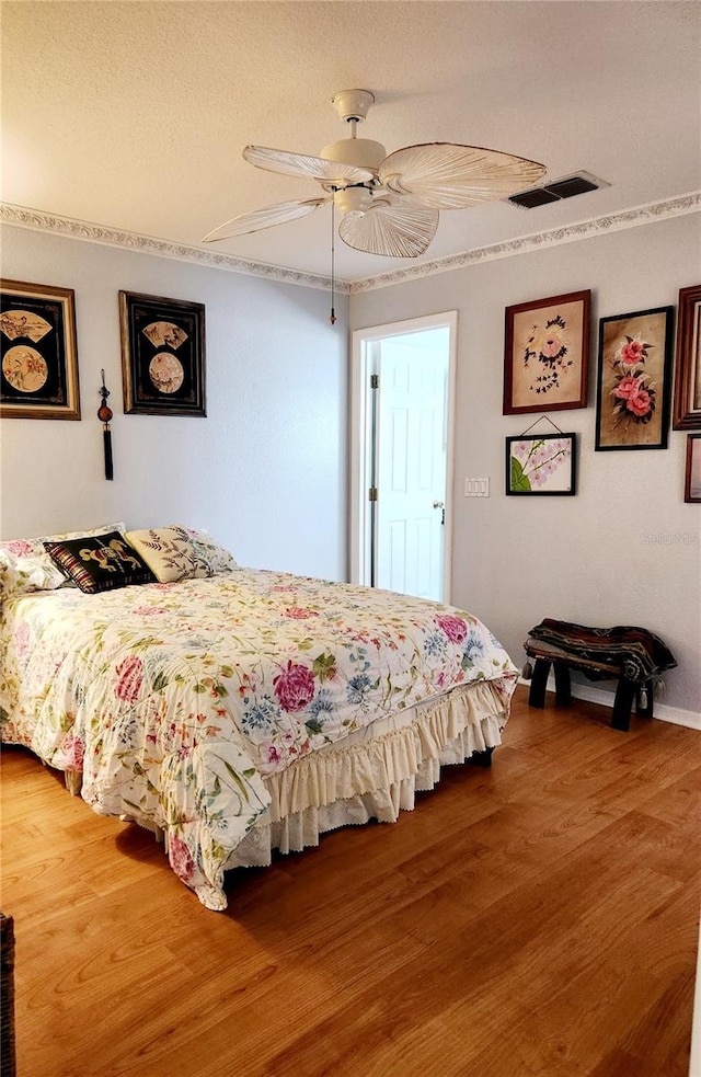 bedroom featuring visible vents, ceiling fan, and wood finished floors