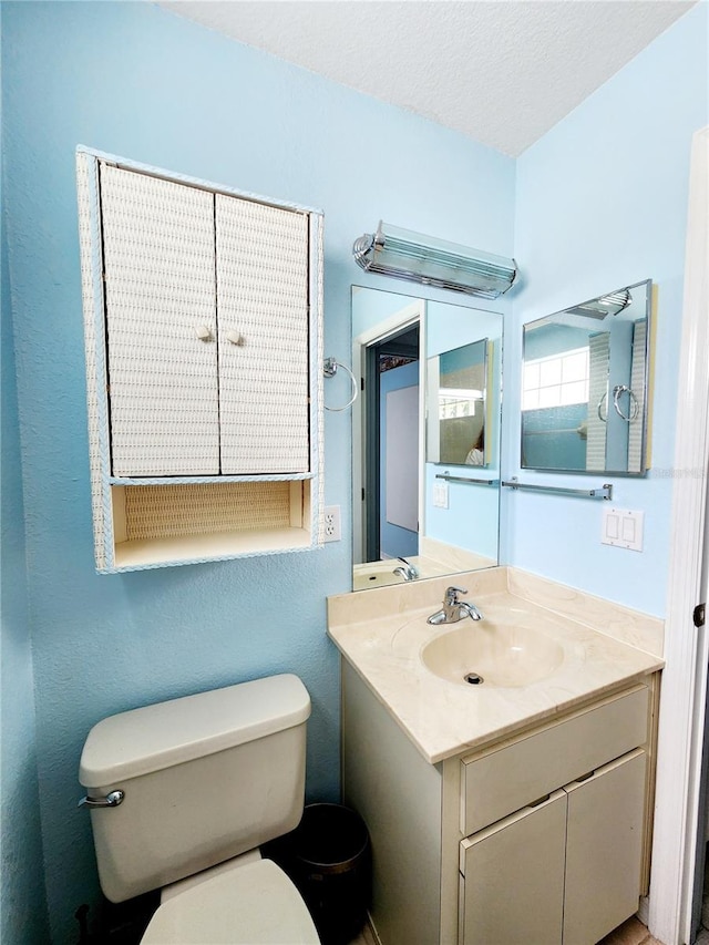 bathroom featuring vanity, a textured ceiling, and toilet