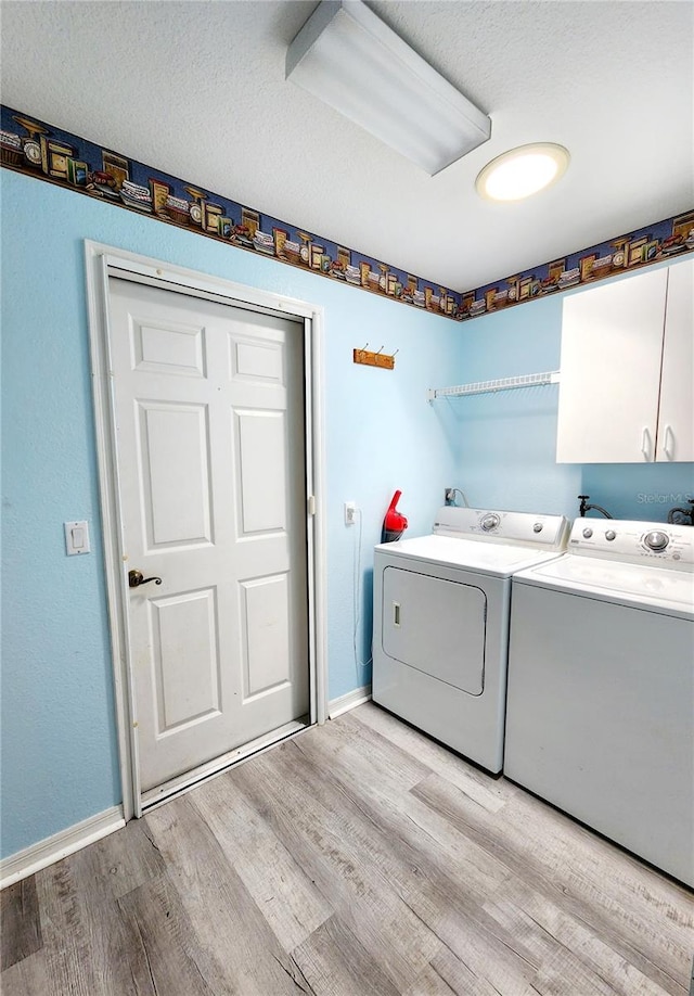 laundry room featuring cabinets, independent washer and dryer, light wood-type flooring, and a textured ceiling